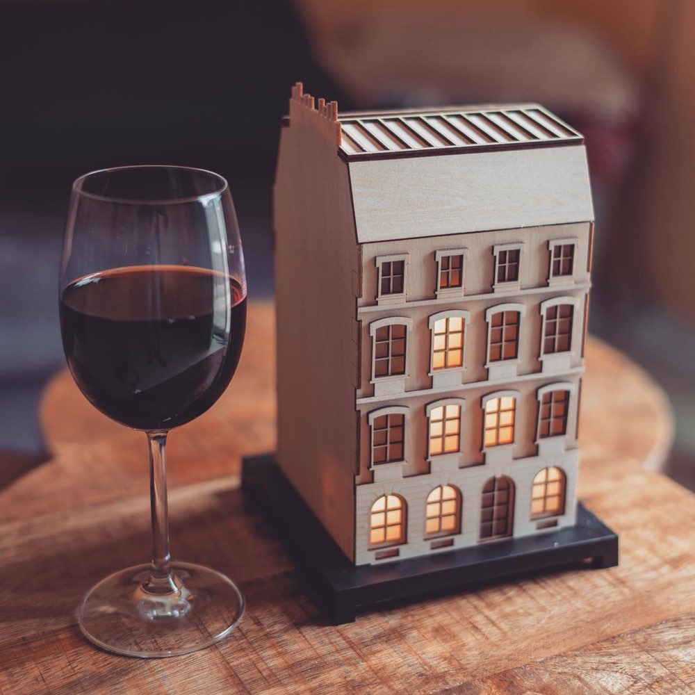 The City Clock lit up on a table, next to a glass of wine